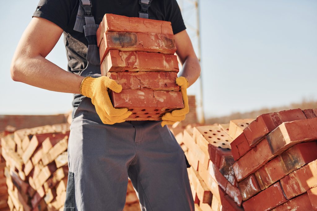 A man with bricks in his hands exemplifies the craftsmanship of masonry, highlighting his role in construction projects.